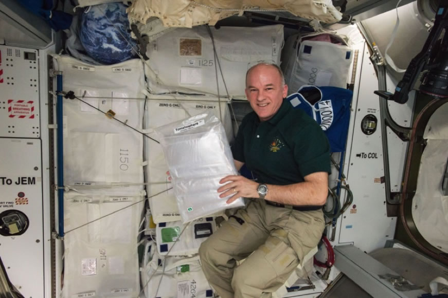 NASA Astronaut Jeff Williams floating in the International Space Station with 1.2 million Tomatosphere™ seeds